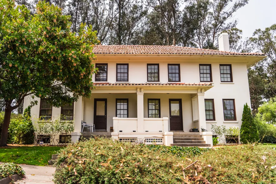 A two-story white stucco building with a red tile roof and two separate front doors under a shared columned porch — duplex insurance in New Jersey